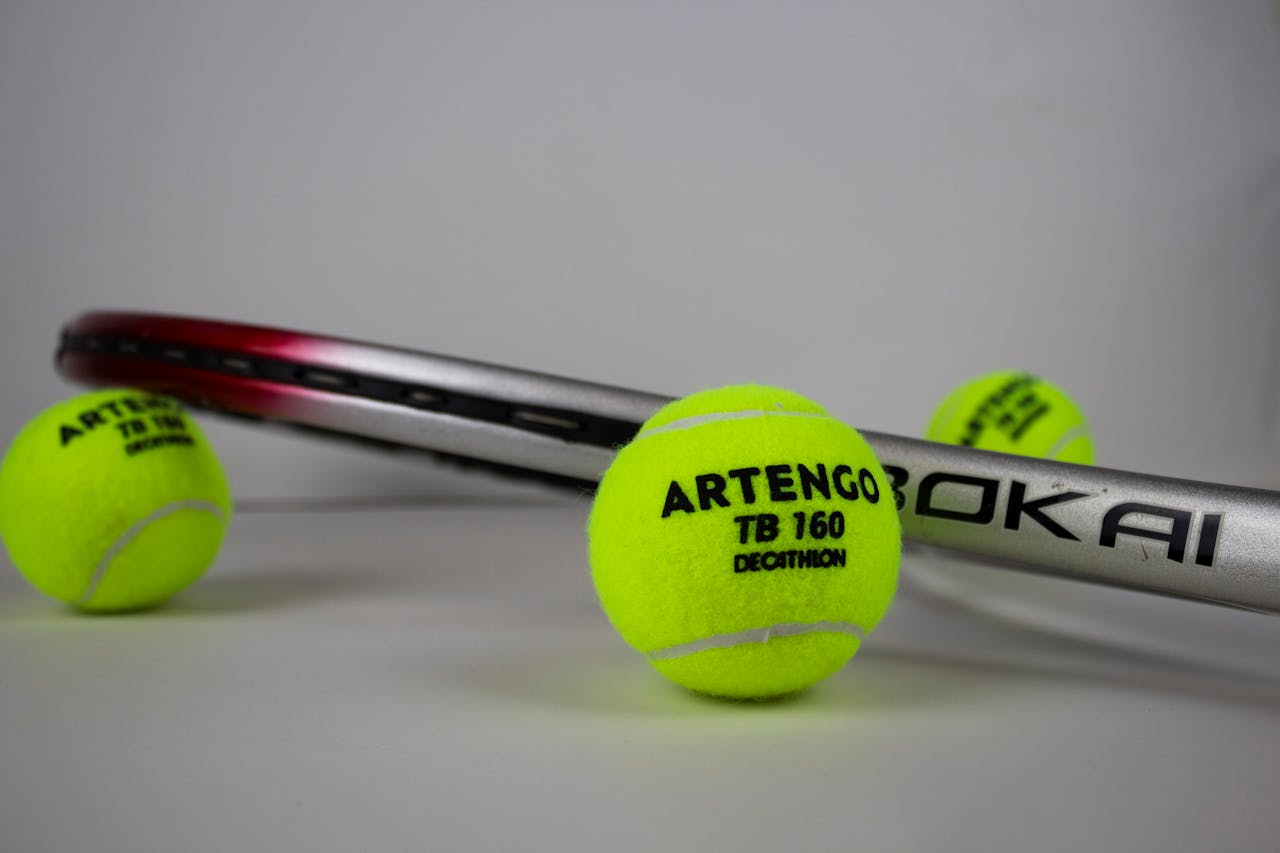 Close-up of a tennis racket with Artengo tennis balls in a studio setting.