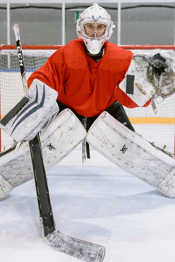 A focused ice hockey goalie in full gear guarding the net during a game.